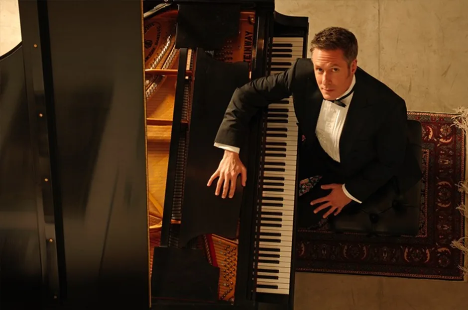 Keith Snell in evening dress seated at a grand piano, photographed from above