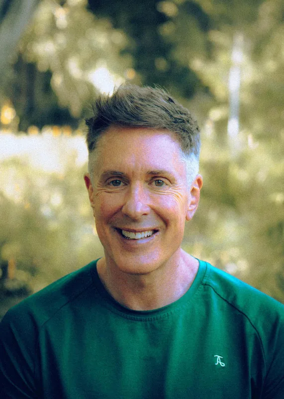 Keith Snell, piano teacher in Bath, smiling outdoors in a green top